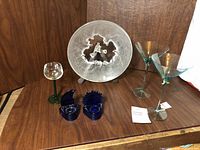 Full view of frosted Hoya art glass plate, martini glasses, and cobalt candle holders on wooden surface