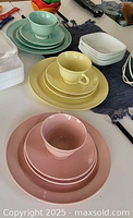 Close-up of three Luray pastel dish sets in pink, yellow, and green showing cups, saucers, and plates arranged on a table