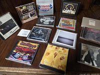 Photo showing a collection of classic rock music CDs from bands such as Lynyrd Skynyrd, Eagles, Led Zeppelin, 38 Special, and Cowboy Junkies on a wooden table.