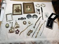 Full display of vintage jewelry assortment including framed pictures, brooches, bracelets, medallions, and small decorative dishes.