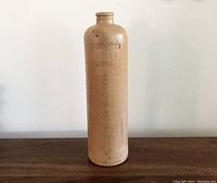 Front side showing embossed markings stamped Amsterdam on the tall stoneware bottle.