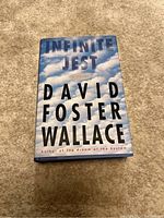 Front cover of Infinite Jest hardcover showing author's name and title over cloudy sky background.