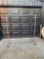 Front view of the heavy duty tubular chrome garment rack showing the full rack standing upright with a garage door in the background.