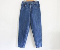 Front full view of the vintage 90s Club Monaco jeans hanging, showing tapered leg and blue medium wash denim.