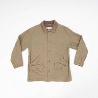 Full view of vintage Columbia chore coat laid flat, showing tan color, brown collar, button front, and pockets.