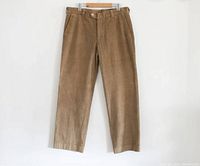 Front view of vintage khaki corduroy pants hanging on hanger against white background.