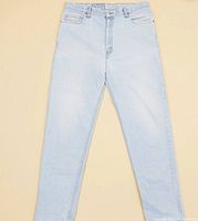 Front view of vintage Levi's light wash denim jeans laid flat showing color and fit, with minor discoloration visible on knee area.