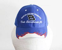 Front view of blue baseball cap with 'NASCAR Racing Champion', 'Dale Earnhardt Jr' and number 8 embroidered logos, red and white flame embroidery on brim.