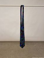 Full view of the slim tie hanging showing length and overall pattern in cool colors
