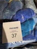 Multiple bags of assorted colored wool felting fibres photographed on floor with MaxSold lot tag 37.
