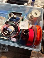 Top view of a plastic bin filled with numerous ribbon spools in a variety of colors and widths, plus bundles of thread and small crafting materials inside a small blue basket.