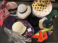 Group photo showing all hats arranged on a surface including various styles and colors, also showing scarves, mannequin head, and hat box