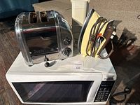 Panasonic microwave front panel with keypad and door closed, Dualit toaster and iron on top.