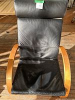 Black leather chair with wooden curved armrests and frame photographed from above, showing wear and some creases on the leather surface.