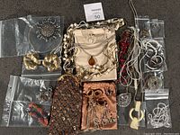 Full assortment of the jewelry lot displayed on a dark surface showing various items arranged with clear plastic bags and gift pouches.