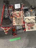 Photo showing all jewelry items including necklaces, ring, earrings, bracelets, brooch, and gift bags arranged on a gray surface