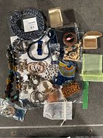 Photo showing the entire lot arranged on a flat surface, including jewelry, scarves, and packaging items.