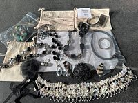 Overview of all jewelry including necklaces, bracelets, brooches, earrings, and scarves displayed on a light background.