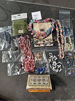 Full view of jewelry assortment on a grey surface showing mixed necklaces, rings, and gift bags.