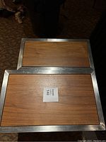 Top view of two rectangular nesting tables showing wood surfaces with metal frames.
