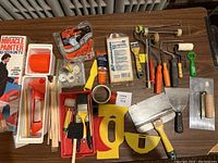 Full spread of all painting tools on wooden table including rollers, trays, brushes, scrapers, and original Miracle Painter kit with packaging.