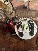 Wide view of both the Shark handheld steamer and the Revitive foot circulation booster showing their physical condition and cords.