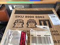 Closed cardboard box labeled with SKU and handling instructions for safety lift.