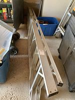 Full length view of the aluminum step ladder with steps visible and rubber feet at bottom.