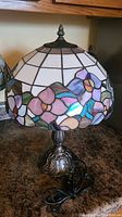 Front view of stained glass style floral acrylic shade and ornate metal base lamp