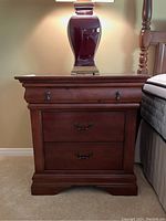 Front view of the wood 3-drawer nightstand showing drawer fronts and metal handles