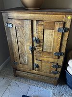 Front view of oak ice box showing double doors and metal hardware
