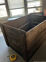 Wooden antique crate showing inside bottom and side panels, demonstrating construction and size compared to measuring tape