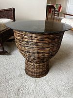 Full view of the smoked glass topped wicker side table on carpet.