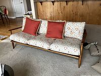 Full front view of sofa with floral cushions and red pillows in living room