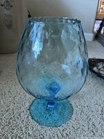 Photo of blue Murano glass art piece with diamond optic texture, showing rounded bowl shape and footed base.