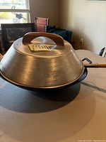 Side view of the carbon steel wok showing the bowl shape and wooden handle with lid on top