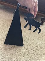 Photo showing the black iron pyramidal wind bell with a moose-shaped windcatcher being held by a hand.