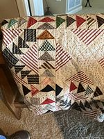 Antique hand quilted quilt draped over oak quilt stand showing detailed patchwork and quilting patterns.