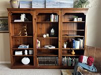 Front view of the Thomasville solid wood adjustable bookcase with various decorative items and books placed on shelves.