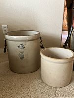 Two stoneware crocks displayed side-by-side, the larger with visible White Hall blue emblem, smaller without markings visible.