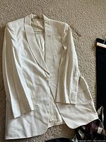 White vintage dinner jacket laid flat showing front and lapel with buttonhole detail.