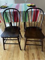 Front view of two walnut bow back dining chairs showing seats, legs, and bow backs.