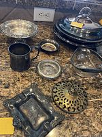 Photo showing all serving and decorative items together on countertop including silver and brass pieces.