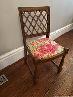 Full view of wooden dining chair showing lattice backrest and floral seat cover, highlighting overall design and condition.