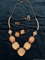 Photo showing entire set with necklace and the three pairs of earrings displayed on dark fabric.