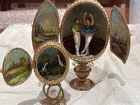 Larger egg open showing ballet dancer figurines inside and smaller egg open with egret bird figurines