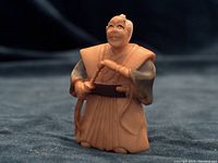 Front view of one antique Japanese Netsuke warrior figurine dressed in traditional robes, holding beaded object.