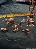 Full set of pewter miniatures including animals (elephants, dog, horse), a cannon, a candelabrum, and other small figurines, placed on a dark fabric background with a ruler for scale.