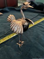 Sterling silver ostrich figurine on surface with measuring tape behind