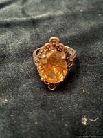 Top view showing oval faceted yellow stone in detailed sterling silver setting with antique style beaded and filigree accents.